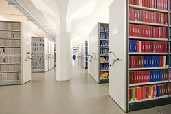 Foto einer Reihe Rollregale mit Einblick auf Gestelle mit ausleihbaren Büchern.